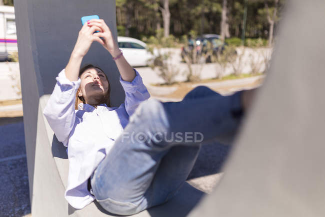 Donna che prende selfie con smartphone mentre si riposa in ombra — Foto stock