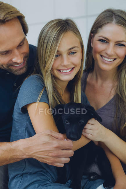 Portrait of smiling father, mother and daughter with puppy — Stock Photo