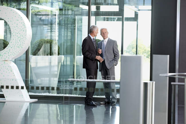 Due uomini d'affari che parlano nella hall dell'ufficio — Foto stock