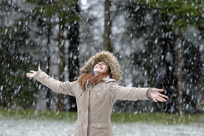 Девушка наслаждается снегопадом, начало зимы — стоковое фото