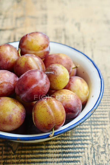Enamel bowl of fresh plums — Stock Photo