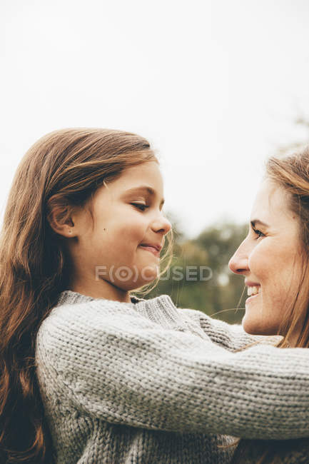 Petite fille étreignant sa mère à l'extérieur — Photo de stock