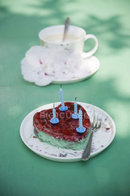 Bolo de aniversário em forma de coração e xícara de café com flores na superfície verde — Fotografia de Stock