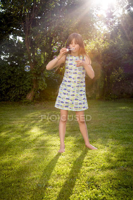 Girl blowing soap bubbles in a garden — Stock Photo