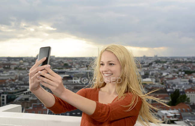 Германия, Берлин, молодая женщина делает селфи со своим смартфоном — стоковое фото