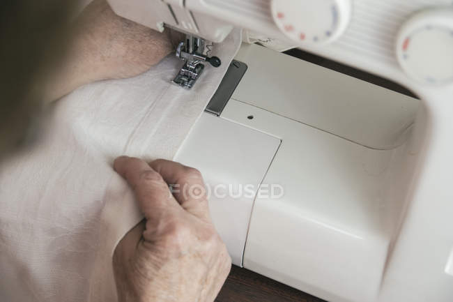 Mains d'une femme utilisant une machine à coudre — Photo de stock