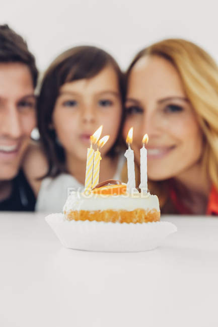 День рождения детей со свечами на торте и семьей на заднем плане — стоковое фото
