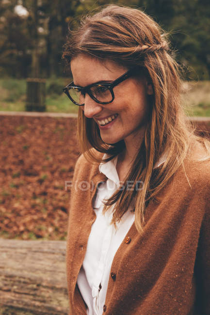 Porträt einer lächelnden jungen Frau mit Brille in einem herbstlichen Park — Stockfoto