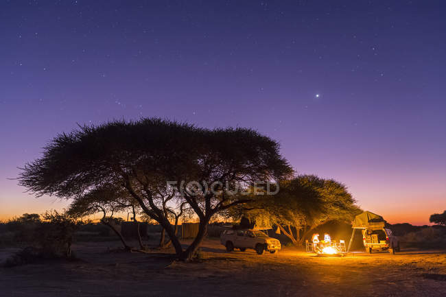 Botswana, Kalahari, Reserva Central de Caza Kalahari, camping y fogata bajo el cielo estrellado - foto de stock