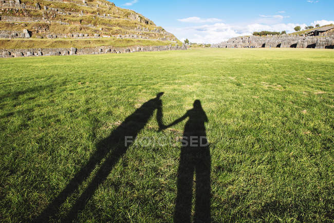 Peru, Cusco, shadow of two travelers visiting Saksaywaman citadel — Stock Photo
