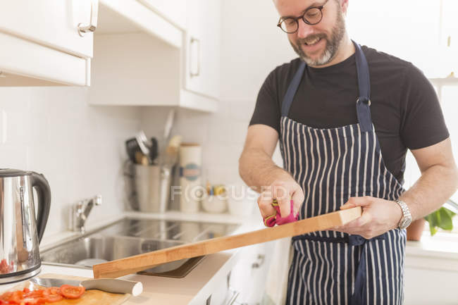Мужчина чистит доску на кухне — стоковое фото