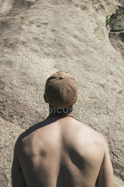 На спине человека без рубашки с дырой, смотрящего на стену перед тем, как взобраться — стоковое фото
