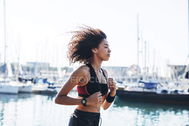 Woman jogging in front of harbor — Stock Photo