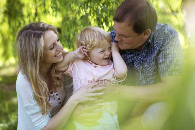 Genitori felici abbracciare il figlio nel parco — Foto stock