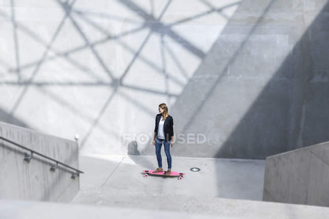 Geschäftsfrau mit rosa Skateboard in moderner Architektur — Stockfoto