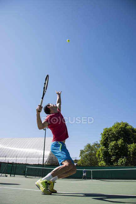 Jogador de tênis que serve uma bola de tênis durante uma partida de tênis — Fotografia de Stock