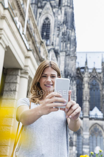 Germania, Colonia, ritratto di una giovane donna che si fa un selfie con lo smartphone — Foto stock