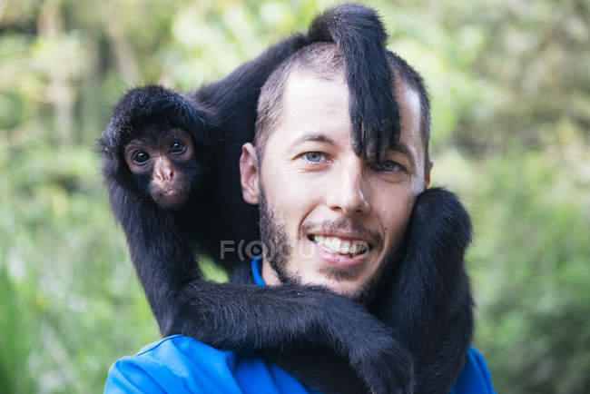 Bolivien, coroico, Porträt eines lächelnden Mannes mit schwarzem Spinnenaffen auf den Schultern — Stockfoto