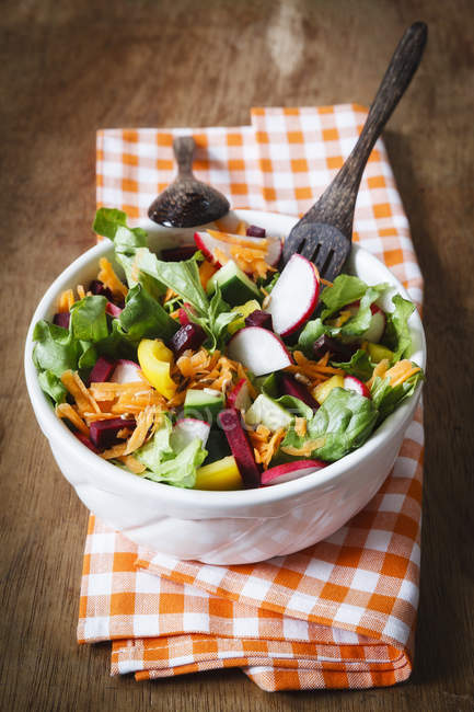 Fresh mixed salad in bowl on wooden background — Stock Photo