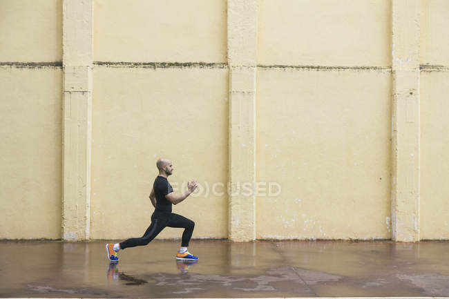 Man doing proper lunge exercise in front of a wall — Stock Photo