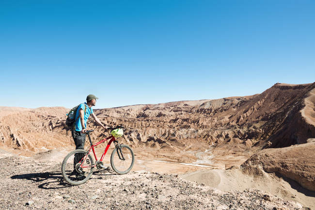 Chile, Man holding a mountain bike and looking to the Death Valley in the Atacama Desert — Stock Photo