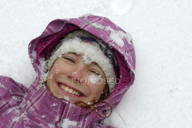 Ritratto di ragazza sorridente sdraiata sulla neve — Foto stock