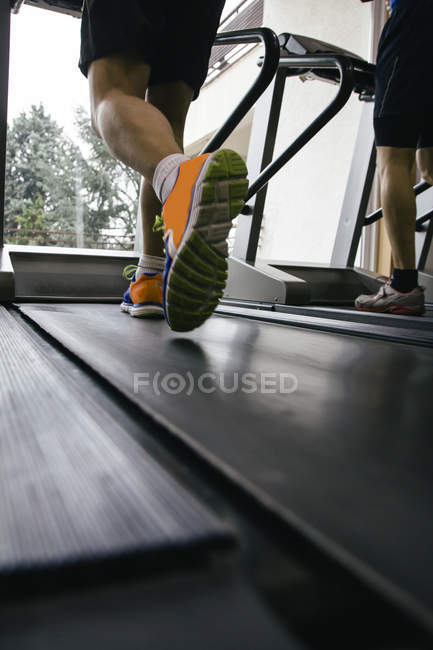 Частичный взгляд на ноги спортсменов мужского пола, бегающих на беговой дорожке — низкий раздел, Жизненность - Stock Photo