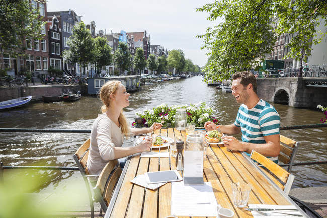 Netherlands, Amsterdam, happy couple having lunch at town canal — Stock Photo