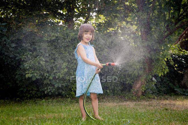 Little girl playing with garden hose — Stock Photo