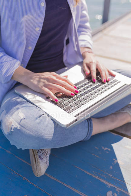 Primo piano di donna utilizzando il computer portatile sul molo — Foto stock