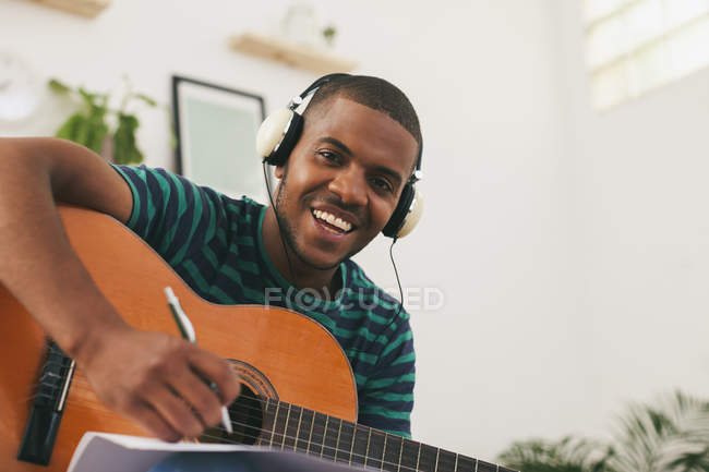 Homme avec guitare écouter de la musique avec écouteurs — Photo de stock