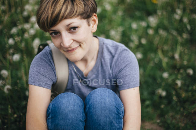 Портрет усміхнений молода жінка, сидячи на луг — стокове фото