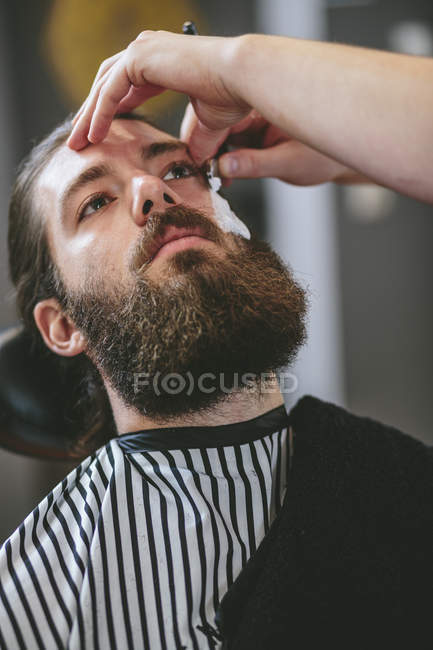 Крупним планом Чоловік з повною бородою отримує гоління в перукарні — стокове фото