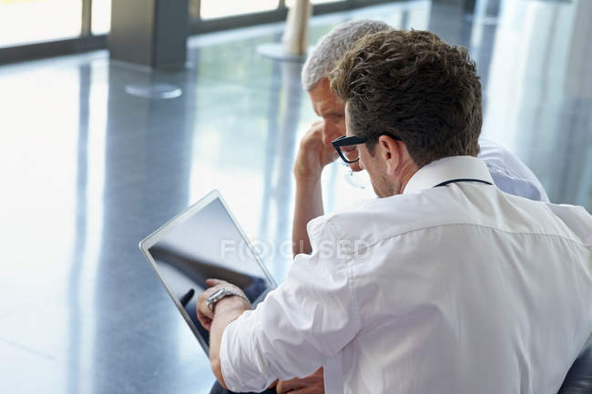 Two businessmen using laptop in office lobby — Stock Photo