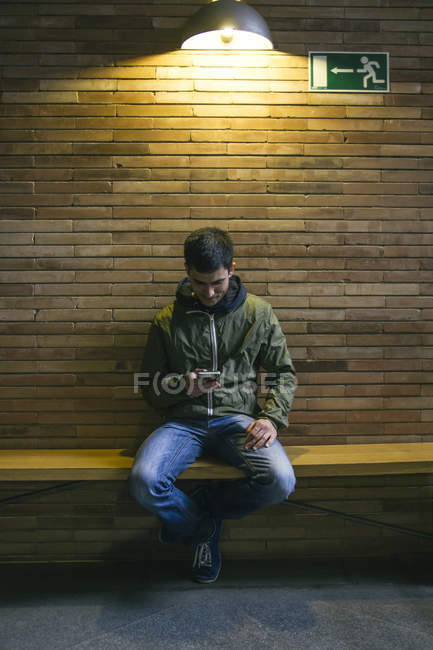 Uomo seduto su una panchina a guardare il suo smartphone — Foto stock