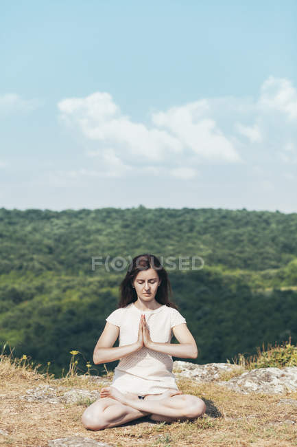 Giovane donna che medita sulla scogliera — Foto stock