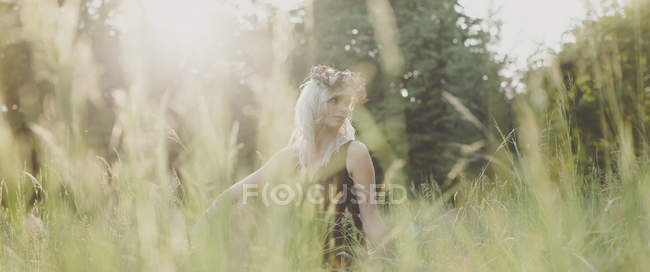 Menina com flores no cabelo durante o pôr do sol — Fotografia de Stock