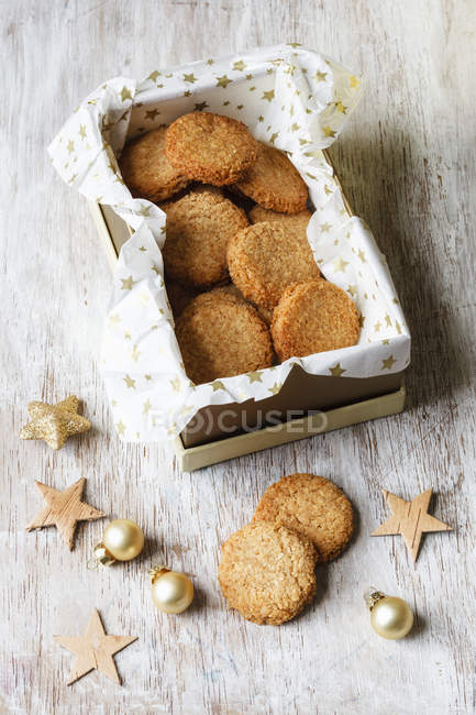 Boîte de biscuits au coco à grains entiers et décorations de Noël sur bois — Photo de stock