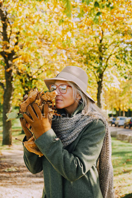 Ritratto di donna che annusa foglie autunnali nelle sue mani — Foto stock