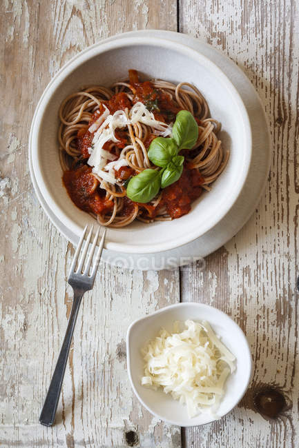 Ciotola con spaghetti di farro integrale, salsa di pomodoro, parmigiano e basilico — Foto stock