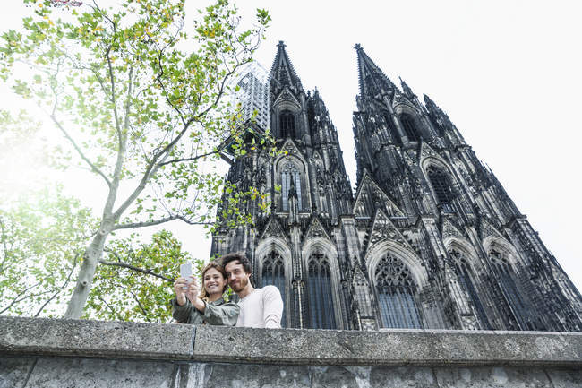 Germania, Colonia, ritratto di una giovane coppia che si fa un selfie davanti alla Cattedrale di Colonia — Foto stock