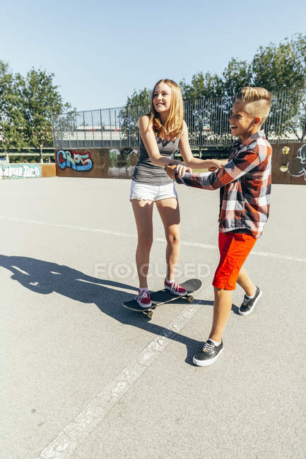 Adolescent garçon enseignement copine skateboard — Photo de stock