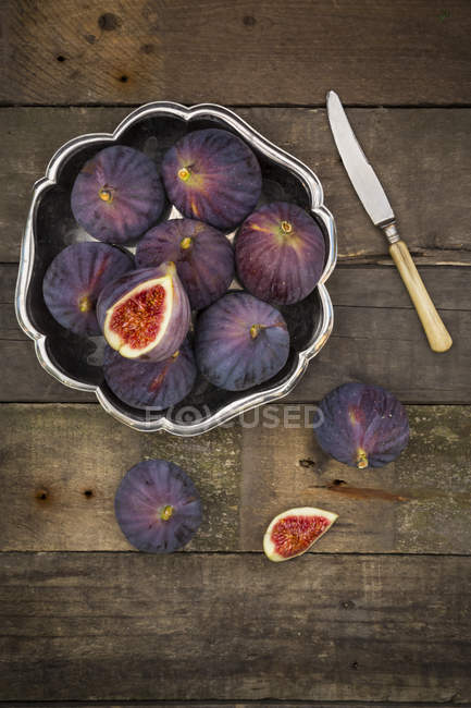 Bowl of figs and a knife on dark wood — Stock Photo