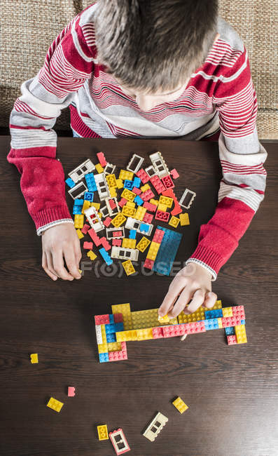 Garçon jouer avec la construction de briques sur une table — Photo de stock
