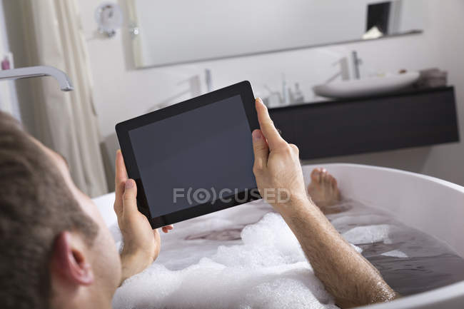 Uomo con tablet digitale seduto nella vasca da bagno — Foto stock