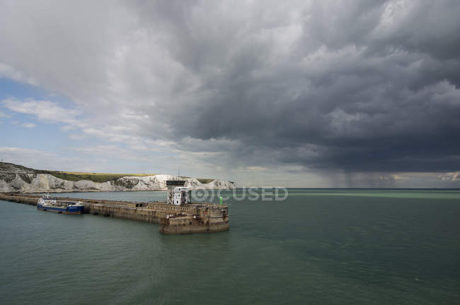 Gran Bretaña, Inglaterra, Dover, barco de carga en el puerto, acantilados blancos y tormenta en el fondo - foto de stock