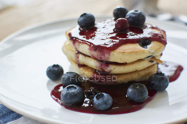 Lemon blueberry pancakes with blueberry syrup on white plate — Stock Photo