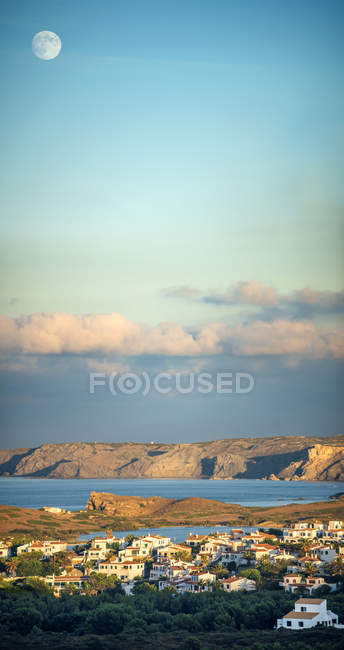 Spanien, Balearen, Menorca, Blick auf die Bucht von Cala bei Sonnenuntergang mit dem Mond am Himmel — Stockfoto