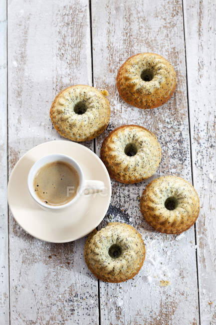 Cinco mini pasteles Gugelhupf con semillas de amapola y taza de café en madera - foto de stock
