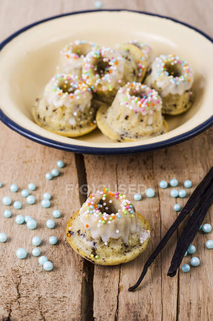 Ciotola di mini torte di marmo alla vaniglia, perle e baccelli di vaniglia su legno — Foto stock